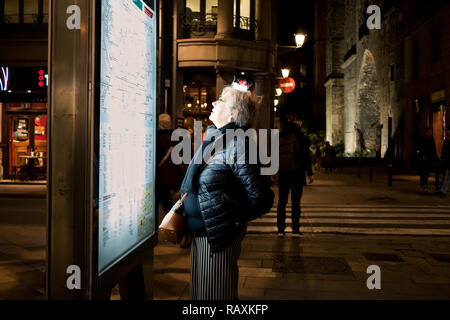 Barcelona, Spanien - 19. Dezember 2018: alte einsame Frau reisen Solo suchen an der Karte von der U-Bahn in der Nacht Stockfoto