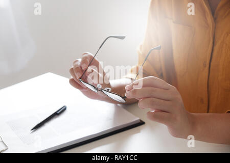 Geschäftsfrau Blick durch ein Vergrößerungsglas zu Dokumenten Hinweis im Büro Stockfoto