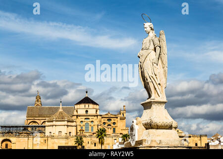 Blick auf die Mezquita Catedral de Cordoba hinter einem Engel Statue an der Römischen Brücke. Einem ehemaligen maurischen Moschee, die jetzt die Kathedrale von Cordoba, Mezqui Stockfoto