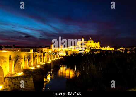 Blick auf die Mezquita Catedral de Cordoba, über die römische Brücke bei Sonnenuntergang. Einem ehemaligen maurischen Moschee, die jetzt die Kathedrale von Cordoba Mezquita ist ein Stockfoto