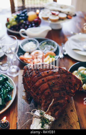 Moderne australische Weihnachtsessen Tabelle mit glasierten Schinken, Garnelen, Kartoffeln und Dill, asiatische Grüns, Christmas Pudding, Hackfleisch Obstkuchen bei Kerzenschein. Stockfoto