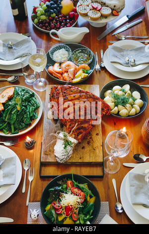 Moderne australische Weihnachtsessen Tabelle mit glasierten Schinken, Garnelen, Kartoffeln und Dill, asiatische Grüns, Christmas Pudding, Hackfleisch Obstkuchen bei Kerzenschein. Stockfoto