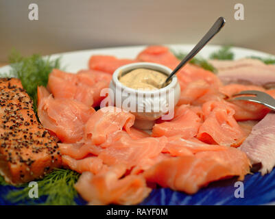 Scheiben geräucherter Lachs auf einer Platte mit gebratenem Lachsfilet, Dill und einem kleinen China Schale mit Senfsauce angeordnet Stockfoto