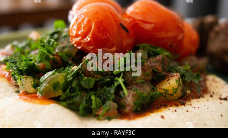 Typische libanesischen Gericht auf Stücke Fleisch basiert gebratene Hackfleisch mit einer Seite der gekochten Tomaten Stockfoto