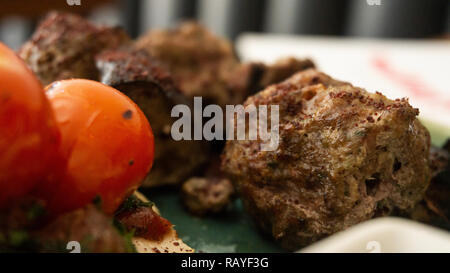 Typische libanesischen Gericht auf Stücke Fleisch basiert gebratene Hackfleisch mit einer Seite der gekochten Tomaten Stockfoto