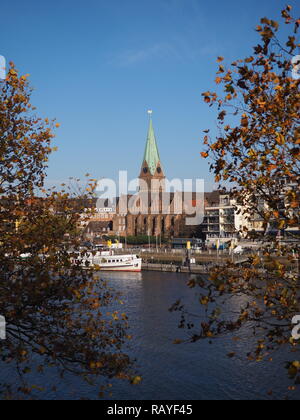 Bremen, Deutschland - Weser mit St. Martini Kirche von Bäumen im Vordergrund gerahmt Stockfoto