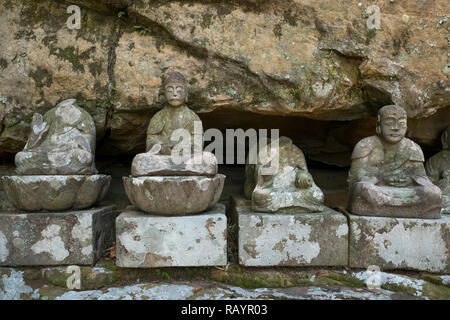 Sasebo, Japan - Oktober 29, 2018: Zeile der gebrochenen alten steinernen Buddha Statuen in Meganeiwa Park, Sasebo Stockfoto