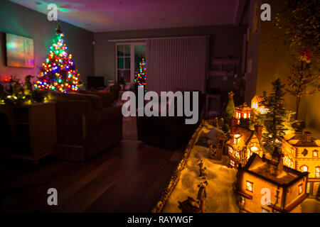 Weihnachtsbaum im Hintergrund und ein Modell Weihnachtsdorf im Vordergrund. Stockfoto