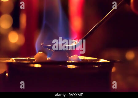 Feuerzangenbowle: blaue Flamme Feuer mit farbigem Hintergrund Stockfoto