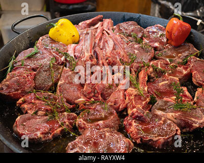 Riesige Pfanne mit rohem Fleisch wie Ribs und Steaks mit Gewürzen und Gemüse fertig vorbereitet für das Kochen Stockfoto