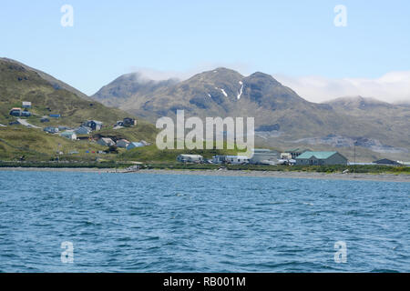 Die Häuser am Rande von Unalaska, auch als Dutch Harbor, von Bergen und dem Beringmeer, Unalaska Island, Alaska, Aleuten Inseln umgeben. Stockfoto