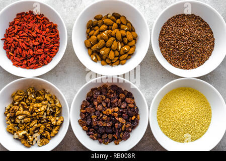 Vegetarisches Frühstück mit gesunden Lebensmitteln Auswahl, Nüsse, Samen, Goji Beeren und andere superfoods auf Tisch, Flach, Overhead Stockfoto