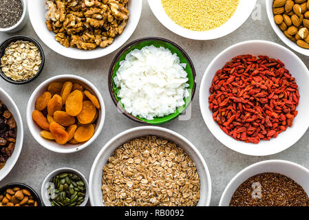 Vegetarisches Frühstück mit gesunden Lebensmitteln Auswahl, Nüsse, Samen, Goji Beeren und andere superfoods auf Tisch, Flach, Overhead Stockfoto