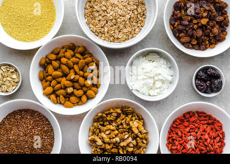 Vegetarisches Frühstück mit gesunden Lebensmitteln Auswahl, Obst, Getreide, Samen, Nüsse, Mandeln, Goji Beeren und andere superfoods auf Tisch, Flach, overhea Stockfoto