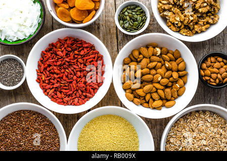 Vegetarisches Frühstück mit gesunden Lebensmitteln Auswahl, Nüsse, Samen, Goji Beeren und andere superfoods auf Tisch, Flach, Overhead Stockfoto