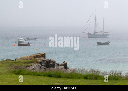 Verankerten Boote. Blick aus dem Dorf, den St. Ronan Bucht, auf der Insel Iona, über den Klang, in Richtung Fionnphort, Mull, Horizont verdunkelt durch frühen Morgen Meer Nebel. ​ Stockfoto