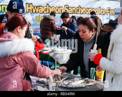 Hwacheon, Südkorea. 5 Jan, 2019. Die Menschen genießen Forellen vom Grill an der Seite eines gefrorenen Flusses während der Sancheoneo Ice Festival in Hwacheon, Südkorea, Jan. 5, 2019. Als einer der größten Winter Veranstaltungen in Südkorea, die jährlichen dreiwöchigen Festival Leute auf dem gefrorenen Fluss, wo die Organisatoren Hwacheon bohren der Löcher im Eis und Forellen in den Fluss während der Festspielzeit zeichnet. In diesem Jahr das Festival dauert vom 5. bis 14.01.27. Credit: Wang Jingqiang/Xinhua/Alamy leben Nachrichten Stockfoto