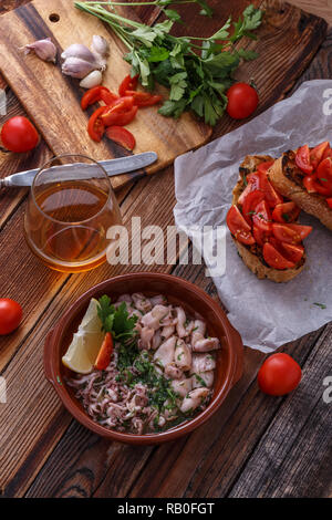 Garlicy baby Tintenfisch mit Tomaten auf knusprigem Brot, spanische Küche. Stockfoto