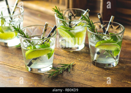 Frischen Cocktail mit Kalk, Eis und Rosmarin, mojito Cocktail in einer Bur auf einem rustikalen Tisch, selektiver Fokus, flacher Tiefe des Feldes. Stockfoto