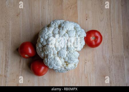 Blumenkohl und Tomaten auf hellem Holztisch. Stockfoto
