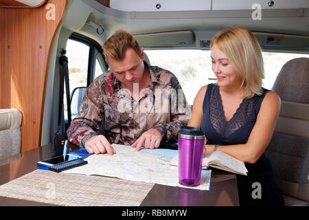 Ehepaar mittleren Alters im Gespräch über die zukünftigen Abenteuer Planung Route bei map in der Freizeit Fahrzeug Motor home Anhänger sitzen. Stockfoto