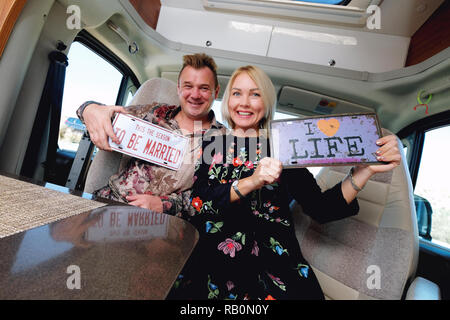 Fröhlich lachend mittleren Alter Familie positive reisende Paar innerhalb von Camper sitzen hält hippy im Retrostil Nummernschild Stockfoto