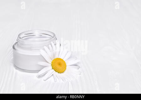 Ein Glas mit Gesicht Creme auf weißem Hintergrund. Biokosmetik mit der Zugabe von kamillenblüten Stockfoto
