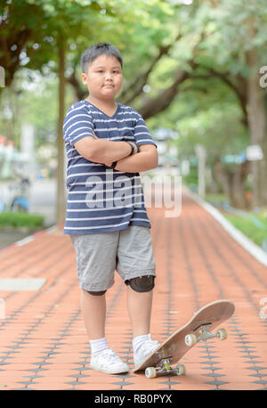 Übergewichtige Junge stand auf Skate Board im Fitness Park, Draußen aktiv Sport für Kinder. Stockfoto