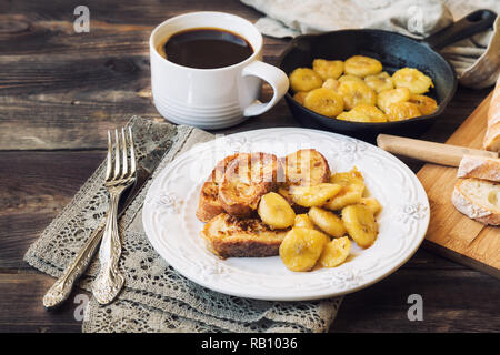 French Toast mit gebratenen Bananen zum Frühstück auf rustikalen Holzmöbeln Hintergrund Stockfoto