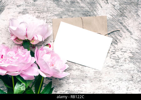 Stilvolle branding Mockup ihre Kunstwerke anzuzeigen. leere Grußkarte oder Einladung Hochzeit mit rosa Pfingstrose Blumen mock up auf Holz- Hintergrund. Stockfoto