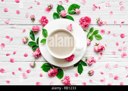 Blumen Komposition. Rahmen aus frischen rosa Blüten mit Tasse Cappuccino auf weißem Holz- Hintergrund. Flach. Mock up. top View Stockfoto