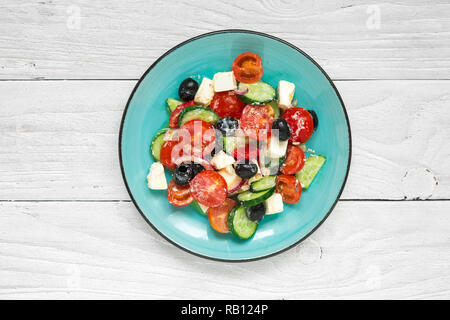 Griechischer Salat mit frischem Gemüse, Schafskäse und schwarzen Oliven in eine Platte auf weiße Holztisch. top View Stockfoto