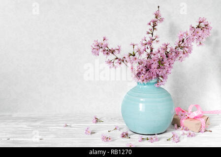 Stillleben mit Blumenstrauß aus kirschblüten Niederlassungen oder Sakura in eine Vase mit Geschenkbox auf weißem Hintergrund. Stockfoto