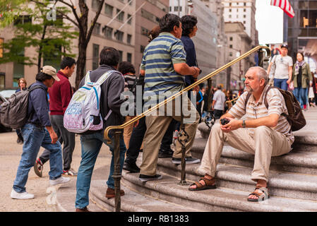 New York, NY, USA - 27. September 2015. Ein Mann sitzt auf der Treppe außerhalb der St Patrick's Cathedral, die als Touristen zu Fuss. Stockfoto