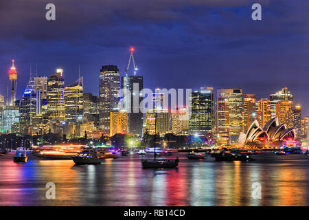 Hell erleuchtete Skyline von Sydney City CBD am Ufer des Hafens von Sydney, mit Lichtern im Wasser spiegelt unter blauem dunklen Himmel. Stockfoto