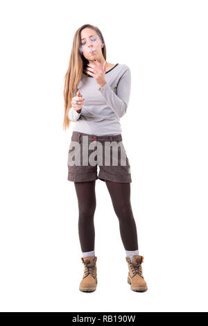 Junge lange Haare blond Hipster stilvolle Frau rauchen Zigarette halten leichter. Voller Körper auf weißem Hintergrund. Stockfoto
