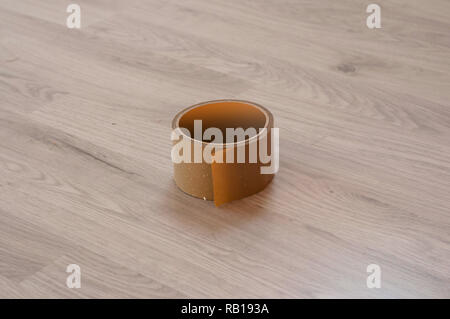 Braun Klebeband auf Holz Laminat Hintergrund. Blick von oben auf ein Klebeband Stockfoto