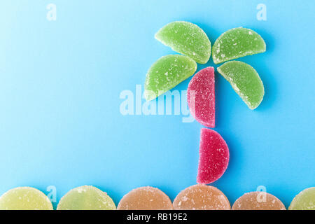 Gelee Royale farbige Scheiben in der Form einer Palme und dem Strand auf einem blauen Hintergrund, Ferienhäuser Konzept Stockfoto