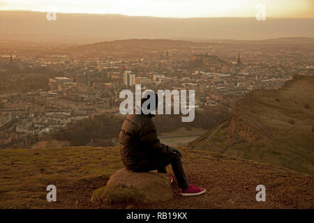 Touristische sitzt auf Felsen über der Stadt Edinburgh, Schottland, Großbritannien, Europa suchen Stockfoto