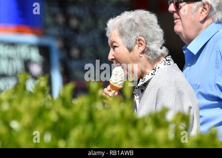 Senior Paar auf einer Promenade an einem warmen Frühlingstag in Großbritannien, essen Eis. Stockfoto