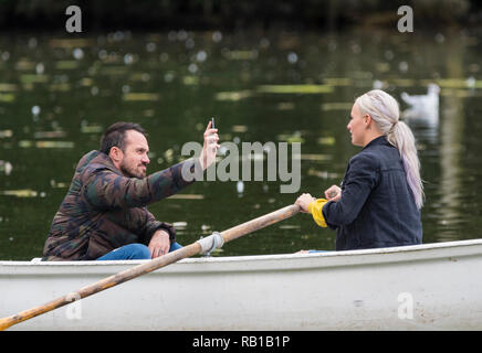 Ein Mann ein Foto einer Frau in einem Boot auf einem See zum Bootfahren im Sommer, im Swanbourne See, Arundel, West Sussex, England, UK. Stockfoto