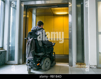 Behinderte Männchen auf dem Rollstuhl im Aufzug gehen Stockfoto