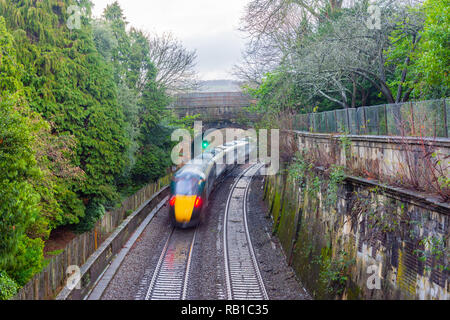 Ein fahrender Zug von oben gesehen mit Bewegungsunschärfe durch Sidney Gärten und unter dem beckford Straße Brücke in der Stadt Bath Somerset UK gehen Stockfoto