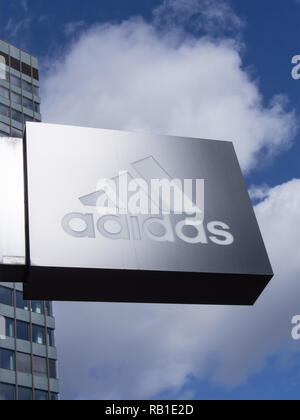 BERLIN, DEUTSCHLAND - 8 April 2017: Glänzende Adidas Logo Vor einem Store in Berlin mit einem Blauen bewölkten Himmel Stockfoto