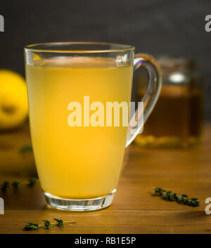 Glas Becher Heiße Zitrone, Honig und Ingwer Drink mit Zweige Thymian Als cold Remedy Stockfoto