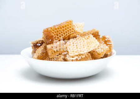Stücke von Bienenwaben in eine Schüssel geben. Frische Biene Honig in honeycomb Stücke auf weißem Hintergrund. Stockfoto
