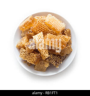 Stücke von Bienenwaben in eine Schüssel geben. Frische Biene Honig in honeycomb Stücke auf weißem Hintergrund. Stockfoto