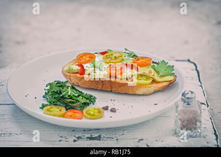 - Nahaufnahme geröstetes Brot mit Avocado und Tomaten serviert mit Grünkohl Stockfoto