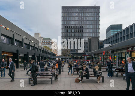 Reisende und Pendler außerhalb von London Euston Station, London, England warten auf Züge und Entspannend Stockfoto