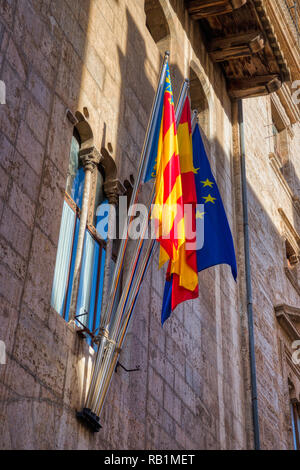 Eine vertikale Foto der leuchtend roten, gelben und blauen EU, spanischen und valencianischen Flags außerhalb eines alten Steingebäude in Valencia hängen Stockfoto